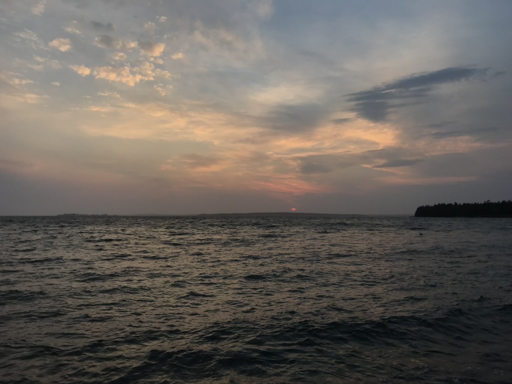 A still lake under a soft sunset sky